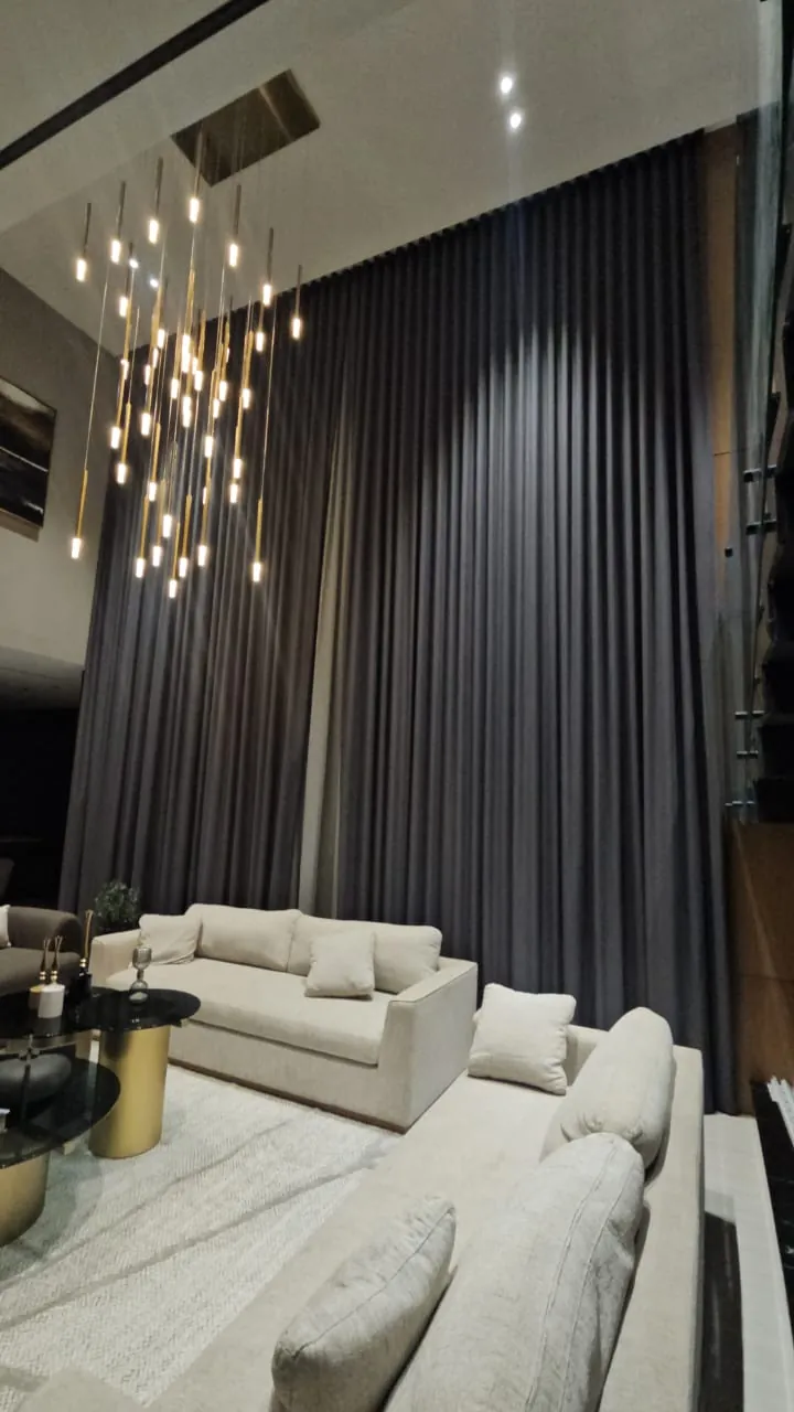 Sala con cortinas oscuras de piso a techo y lámpara colgante